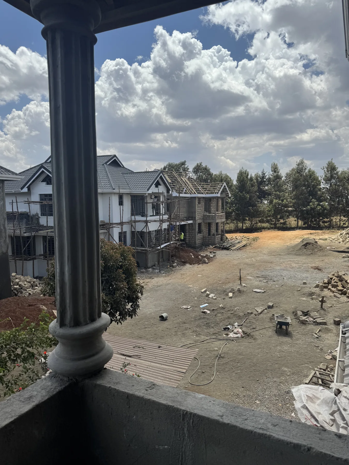 Construction site: the estate road and houses under scaffolding, seen from a balcony