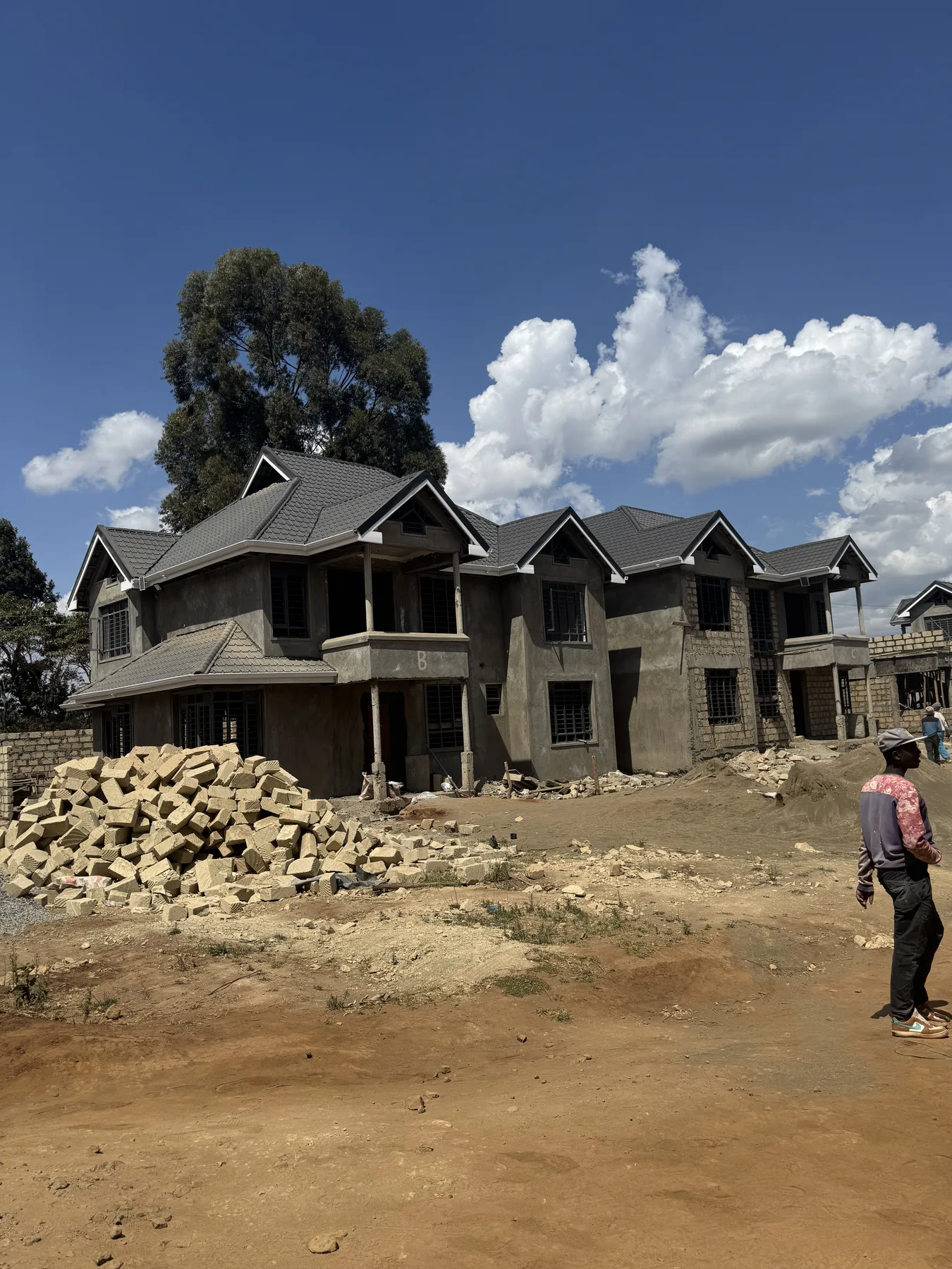 Construction site: roofed house shells, with stacked building stone in the foreground